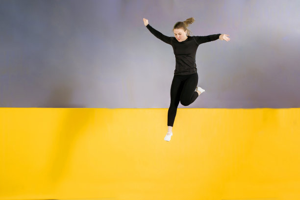 年轻女子业余杂技运动员在室内蹦床上跳跃和锻炼，现代爱好和健身概念图片下载