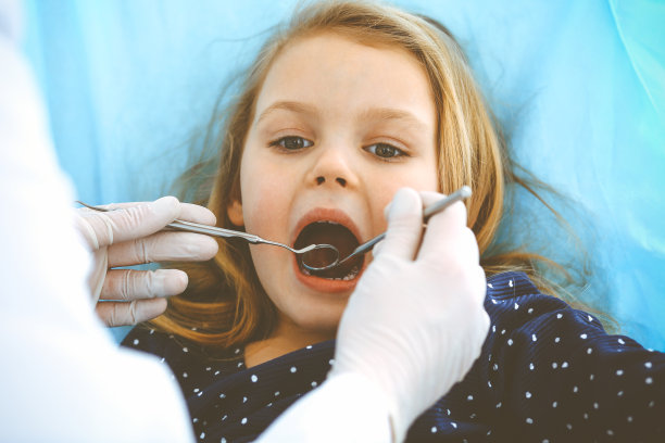 小女孩张大嘴巴坐在牙科椅上接受医生的口腔检查。拜访牙医的办公室。医学概念。健美的照片图片下载