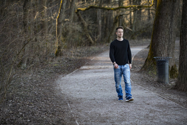 冬末，穿着便服的年轻成年男子走在公园的小路上图片下载
