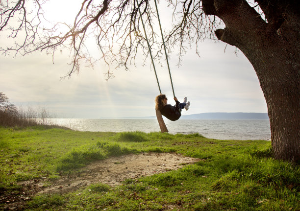 女人在海岸附近荡秋千。图片下载