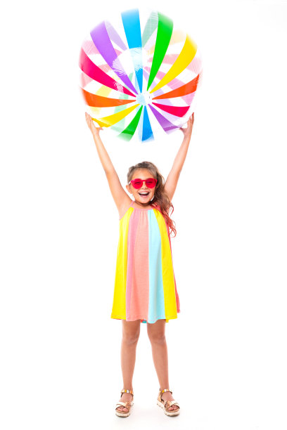 十几岁的白人女孩与色彩鲜艳的衣服持有大橡胶球孤立的白色背景图片下载