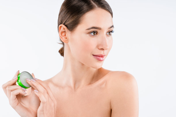 漂亮的年轻女人拿着balm治疗乳液与远离孤立的白色背景图片下载