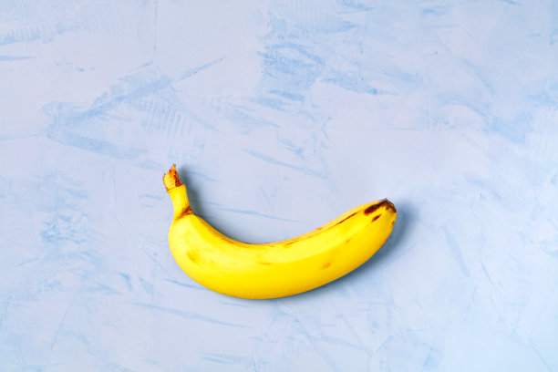 成熟的黄香蕉躺在蓝色的混凝土背景上。图片下载