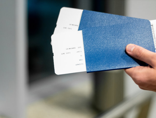 蓝色护照，一个男人手里拿着一张票。股票的照片。机场的亮丽色彩图片下载