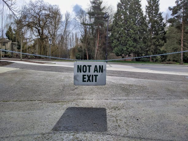 一个挂在链条上的出口标志，挡住了通往主干道的入口图片下载