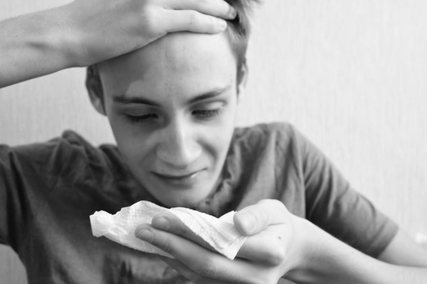 青少年男孩咳嗽并在餐巾纸上擤鼻涕图片下载