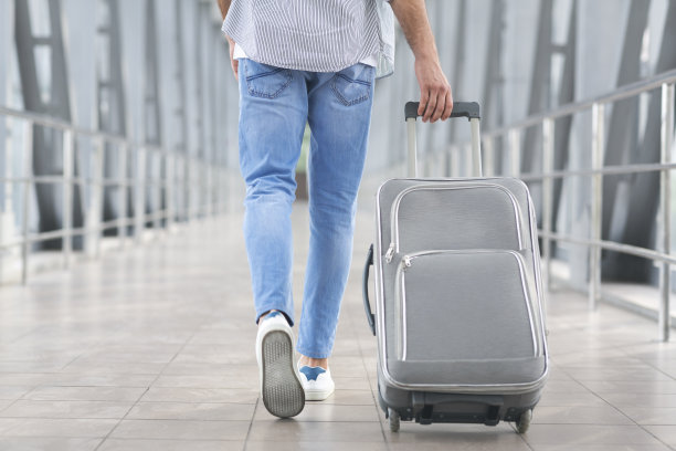 过境旅客概念：在机场航站楼里拿着行李箱的男子图片下载