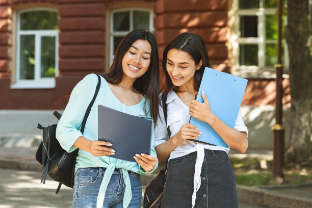 两个微笑的女学生在户外讨论学习项目的肖像图片下载