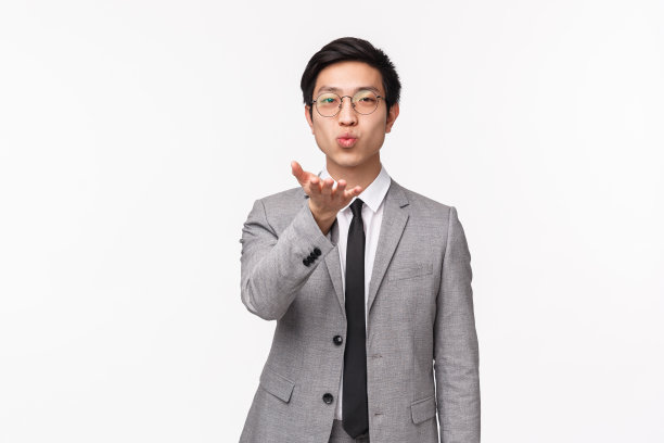 浪漫可爱的英俊亚洲男子身穿灰色西装的半身像，向镜头发送飞吻，去办公室，说再见，女朋友待在家里，站在白色背景前图片下载