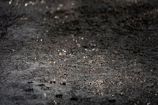 雨落在地面上，黑色的雨天气背景，水泡和水花在水面上，刷新自然上的水滴水模式，美丽的散水滴水图片下载
