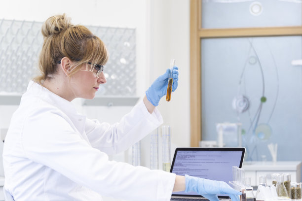 戴眼镜的女化学科学家在实验室研究大麻CBD和CBDa油。她使用乳胶手套、玻璃管和锥形瓶。图片下载