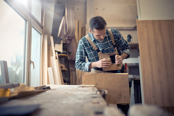 木匠在木工车间用手动刨床刨木板图片下载