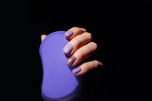 指甲的设计。手与淡紫色的颜色夏季美甲在灰色背景。女性手握发刷的特写。艺术指甲。图片下载