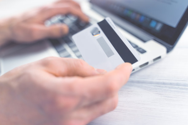 网上购物的概念。男人在线支付。手里拿着银行卡。色调柔和的对焦图片图片下载