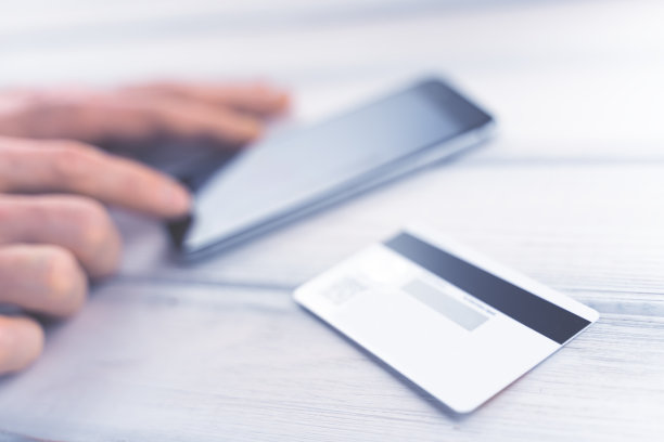 网上购物的概念。男人用智能手机在线支付。银行卡放在桌上。色调柔和的对焦图片图片下载