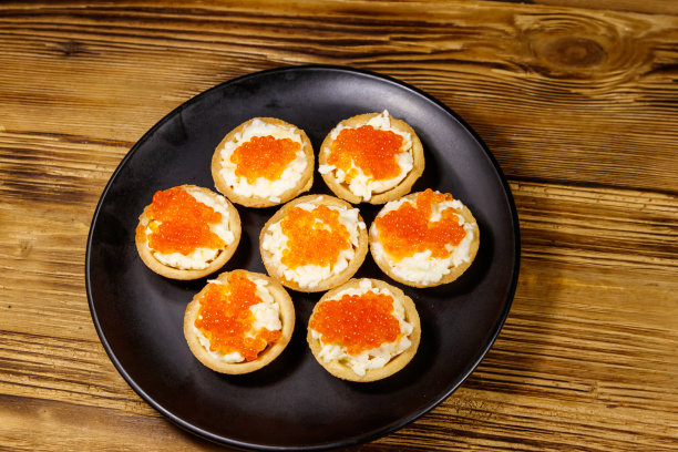 木桌上放着红鱼子酱和软奶酪馅饼图片下载