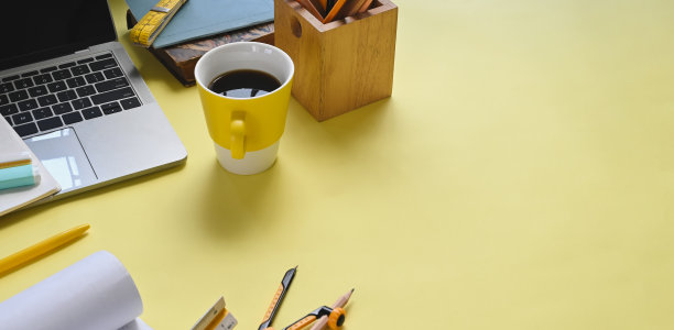 全景横幅杂乱的工作空间。平板电脑笔记本电脑，咖啡杯，笔筒，记号笔，笔记本，铅笔罗盘，卷尺和盆栽在多彩的工作桌上。图片下载