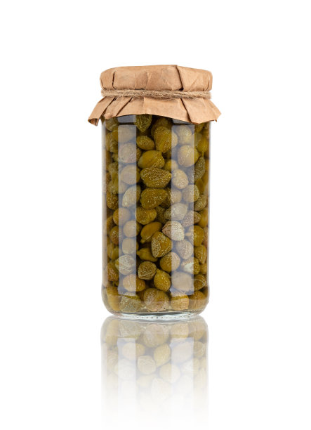 白色背景的玻璃罐子里的山豆。 自制腌酸豆罐子特写。图片下载