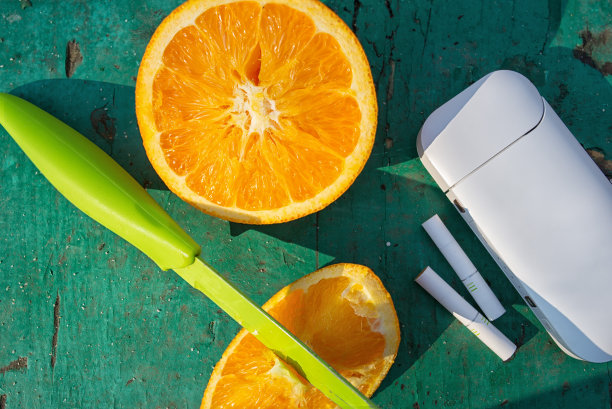 橙色在绿色背景上，刀身在一片橙色中，刀身在绿色中，烟草加热系统与一根烟草棒在一张照片上，半橙色与烟草加热系统与一根烟草棒在一张照片上图片下载