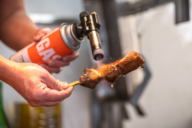 在筑地鱼市，一名男子正在用火焰烹饪新鲜的金枪鱼条图片下载