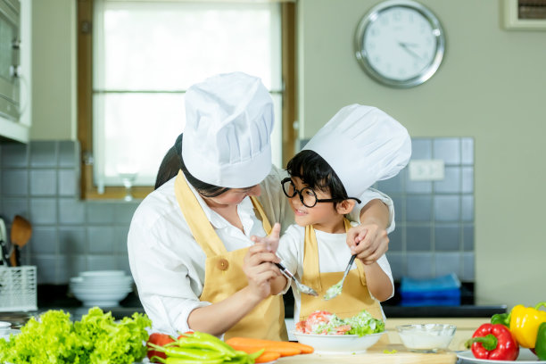 做饭的家庭。厨师父母和孩子为健康饮食制作新鲜蔬菜沙拉。亚洲儿子帮忙做饭，图片下载