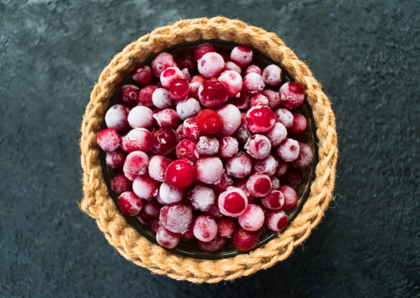 在黑色背景的篮子里装着冰冻的蔓越莓。前视图。图片下载