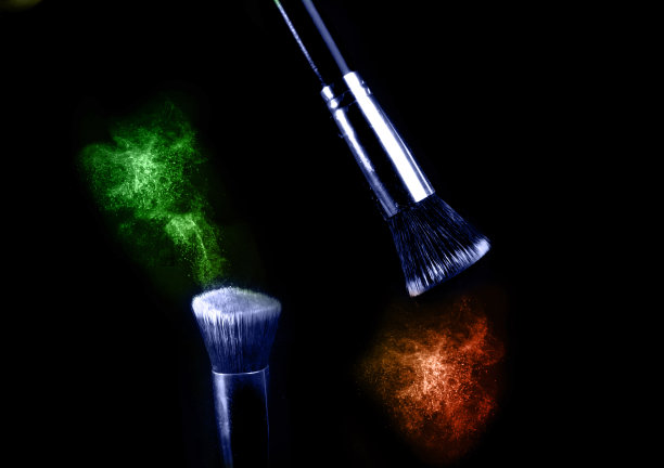 两个化妆刷与飞色粉，产品在黑色背景。简约的黑色是魅力的概念。图片下载