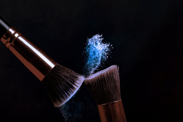 两个化妆刷与飞色粉，产品在黑色背景。简约的黑色是魅力的概念图片下载