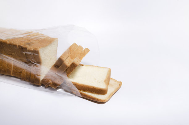 开着的塑料袋里装满了白色背景上的白面包片。早上的烤面包和新鲜的软面包图片下载