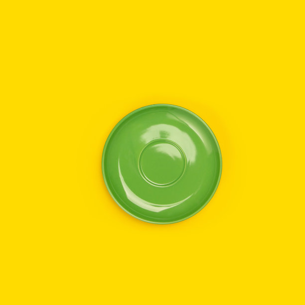 黄色背景上的绿色陶瓷板(碟)俯视图图片下载