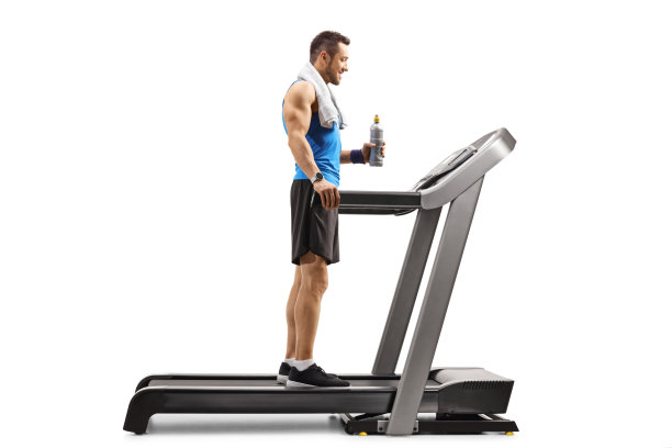一个健康人站在跑步机上拿着一瓶等渗饮料图片下载