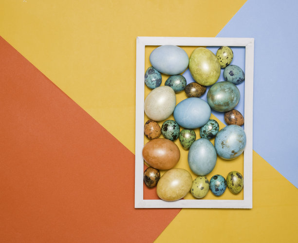 彩色的复活节彩蛋在一个木制的白色框架在彩色的背景。文本的空闲空间。图片下载