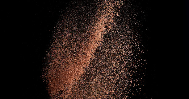 黑色背景上有飞舞的颗粒和可可粉，冰冻的甜点图片下载