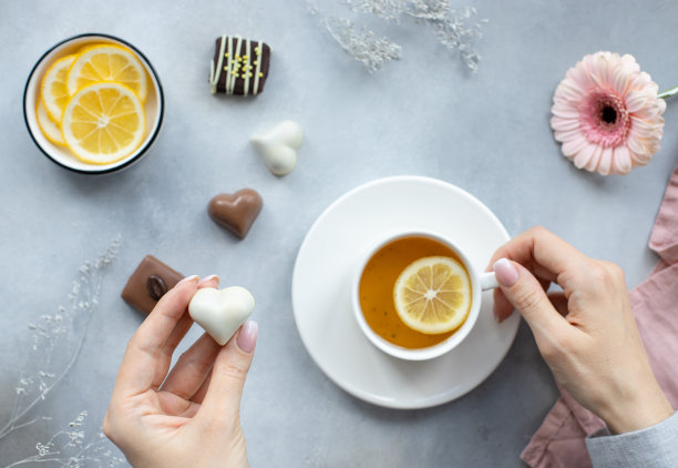 女人的手拿着巧克力心形的糖果和一杯茶图片下载