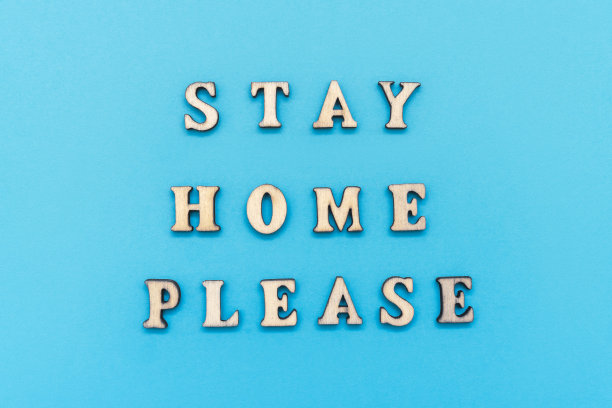 淡蓝色背景木制字母制作的标语“请呆在家里”。冠状病毒大流行防护概念。最小的概念。平躺，俯视图图片下载