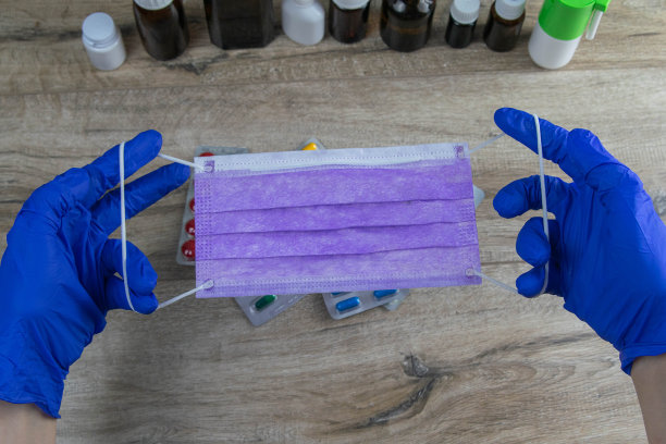 医生、护士或科学家手持医用口罩，手持蓝色丁腈手套以防止感染。Covid-19冠状病毒图片下载