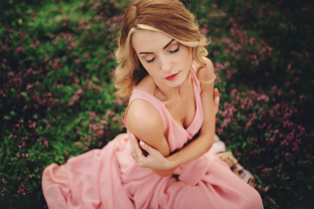 穿着鲜艳鲜花的金发美女。女孩化妆和发型在粉红色的裙子在盛开的春天公园。女人的天图片下载