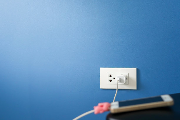 手机适配器和电源插头在深蓝色的墙上。图片下载