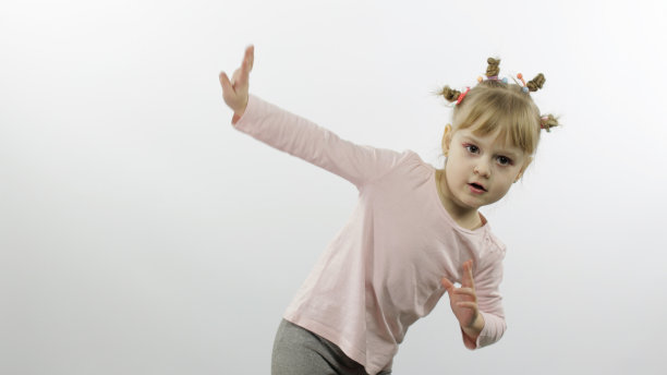 积极的女孩穿着粉红色的衬衫跳舞。快乐的四个小孩。白色背景图片下载