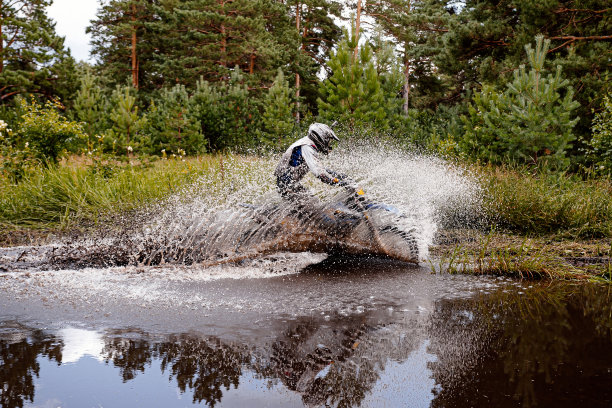摩托车越野者在森林小径上的水坑中骑行图片下载