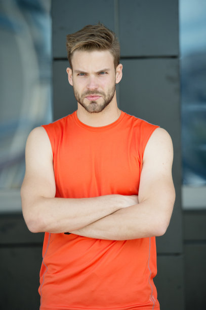 “都市中性男”的概念。有魅力的蓄胡须的男人很在意自己的风格和外表。男子刚毛严厉的脸肌肉发达的肩膀城市背景。留着胡子的男人肌肉发达，看起来帅气又酷图片下载