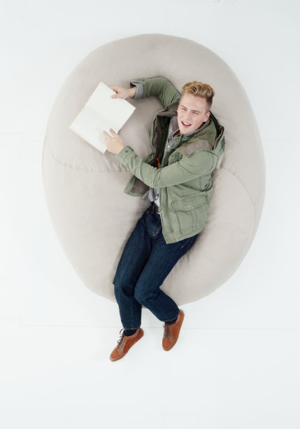 白人男大学生躺在白色背景下，穿着西装，拿着课本图片下载