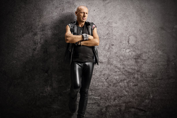 严肃的秃头朋克靠在生锈的墙上图片下载