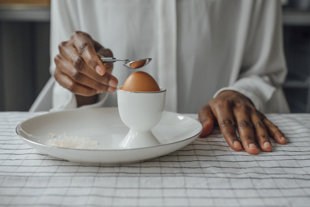 一个女人的手打开一个软煮鸡蛋的早餐图片下载