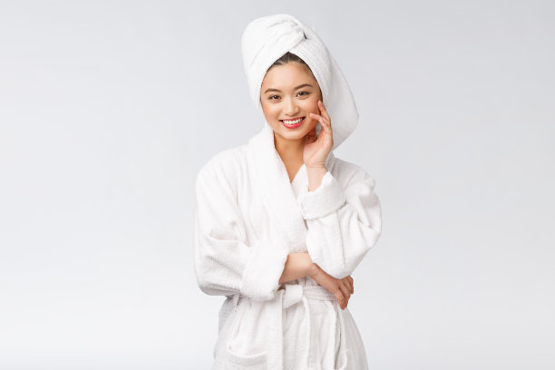 一个年轻快乐的亚洲女士在浴袍的肖像。孤立在白色背景。图片下载