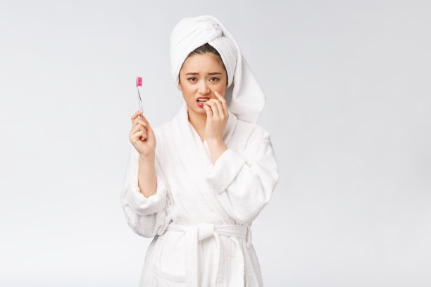 不幸的美丽女人在白色的背景上刷牙图片下载