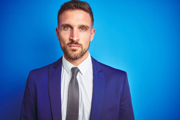 蓝色背景下表情严肃的年轻英俊商务男士特写照片图片下载