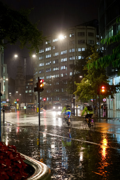 两个骑自行车的人在下雨的街道上图片下载