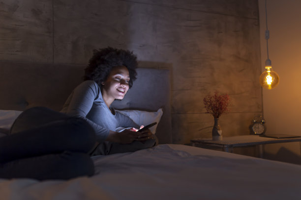 女人躺在床上使用智能手机图片下载