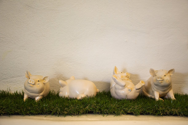 四个小猪娃娃在房间的塑料草装饰上玩耍图片下载